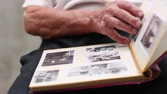 Senior Man Flipping Through The Pages Of A Photo Album