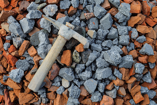 Stones made from broken red bricks and concrete blocks. Hammer pickaxe on a pile of stones.