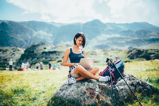 Young woman in the mountain resting and using laptop