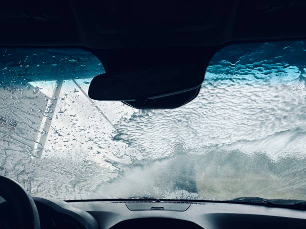 istock Man splash water for car wash cleaning windshield - view from inside. 1919596789