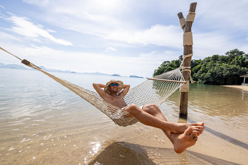 30's man relaxing on hammock over sea in Thailand, Southeast Asia vacations.