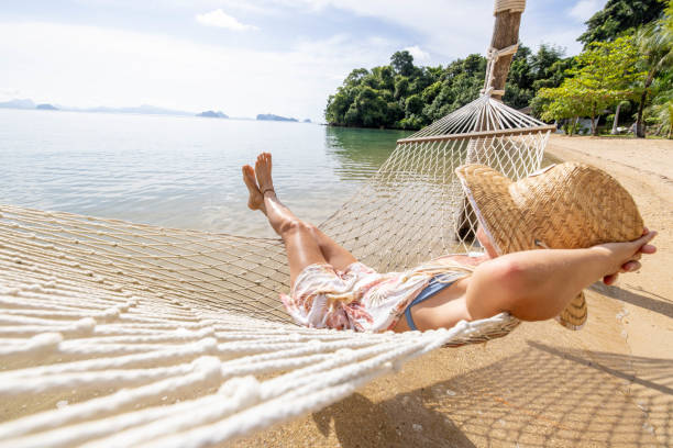 istock Woman relaxing on hammock by the beach at sunrise 1919601694