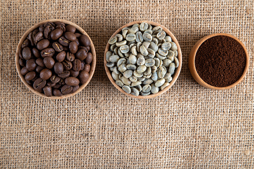 Ground coffee with roasted coffee beans on burlap,above view