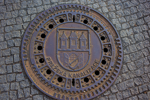 Prague, Czech Republic  October 6, 2023: Unusual manhole cover in Prague. Metal drainage cover on the sidewalk in the historical center of the capital. Decorative manhole cover for city sewerage.