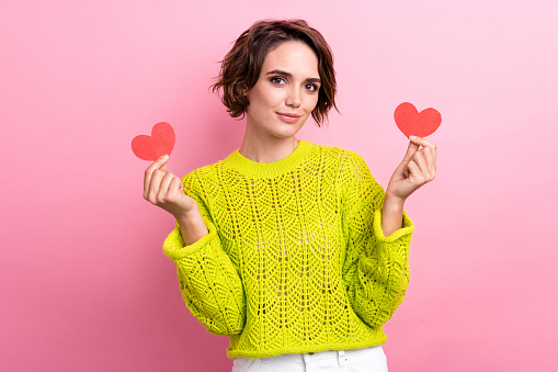 Photo portrait of young cute girlfriend holding two red postcards heart for valentine day surprises isolated on pink color background.