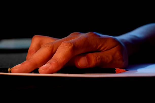istock hand writing on paper illuminated by candlelight. 1919625580