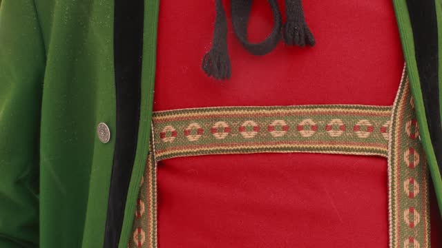 The top part of a men's national costume, a thick green jacket, a red knitted vest and embroidered suspenders for leather trousers