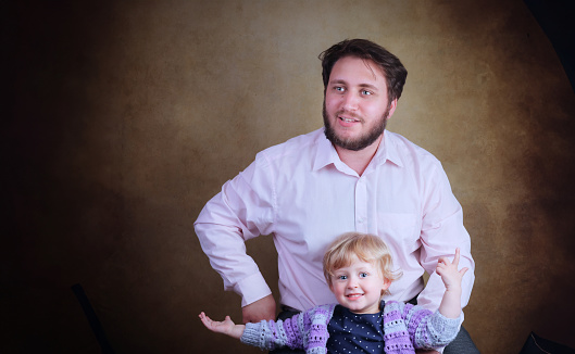 Studio portrait of a happy and contented young Caucasian Dad and his cheeky 3 year old daughter