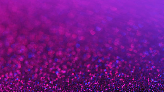 Glitter background. Defocused shimmering. Party sequins. Shiny purple festive confetti in abstract bokeh glimmer art.