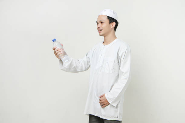 istock asian muslim man holding a water bottle with smile face on isolated background 1919666536
