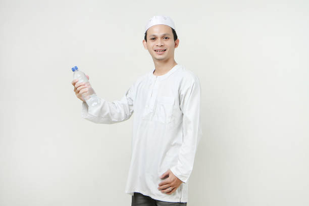 istock asian muslim man holding a water bottle with smile face on isolated background 1919666545