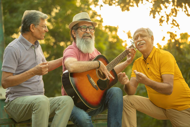 istock Older friends playing guitar and enjoying in park 1919670209