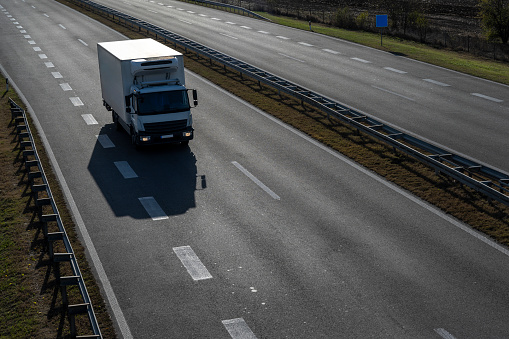 Small truck driving on the highway, Small white delivery truck moving fast on road, distribution business express delivery service. Refrigerated van for the transport of perishable goods.