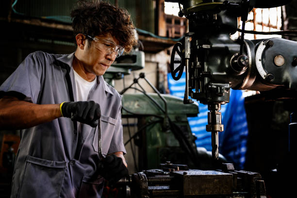 istock Engineer worker in production plant drilling at machine. Professional worker near drilling machine on factory. man inspecting and repairing machine for operation in workshop. 1919720342
