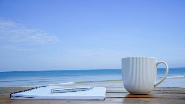 istock Notebook, pens and coffee on a rooftop by the sea 1919723572