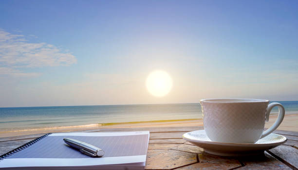 istock Notebook, pens and coffee on a rooftop by the sea 1919723573