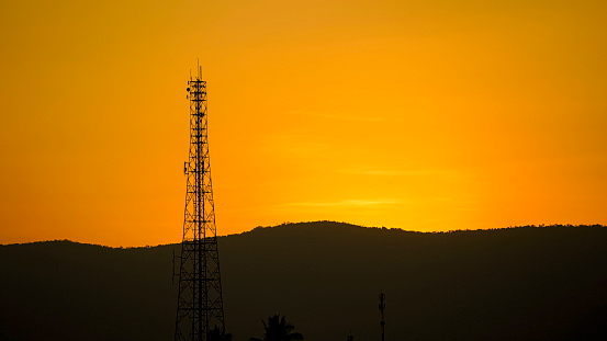 Silhouette, antennas and telecommunication receivers for wireless network signals, sunset background