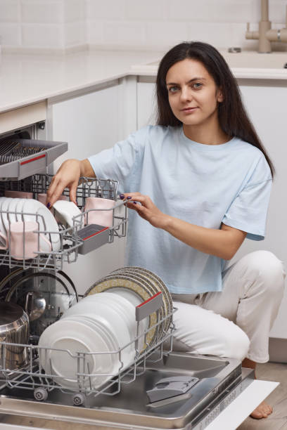 istock pretty woman unloading from open dishwasher machine with clean utensils inside 1919736165