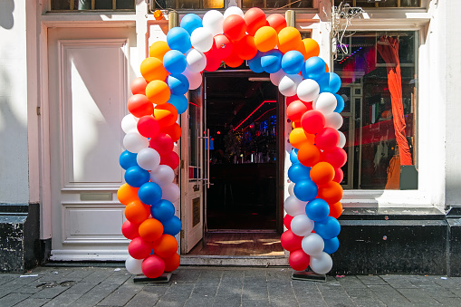 Typical dutch cafe decorated with red, white and blue balloons at kings day in Amsterdam the Netherlands