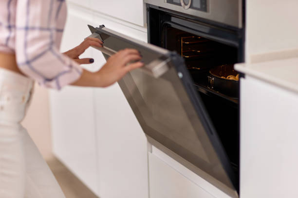 istock female hands put pan of dough into kitchen oven. 1919751450