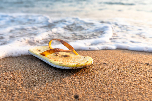 une vieille sandale jaune venant de la mer lorsque les vagues qui frappent le rivage posent un problème environnemental - disposable cup plastic beer bottle photos et images de collection