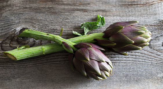 Fresh organic artichokes on wooden background. Healthy and vegetarian food. Overhead view.