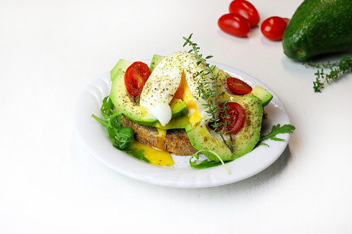 Delicious avocado toast with poached egg and tomato on white background. Healthy food concept. Overhead view.