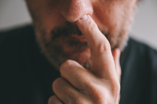 Closeup of male finger picking nose, selective focus