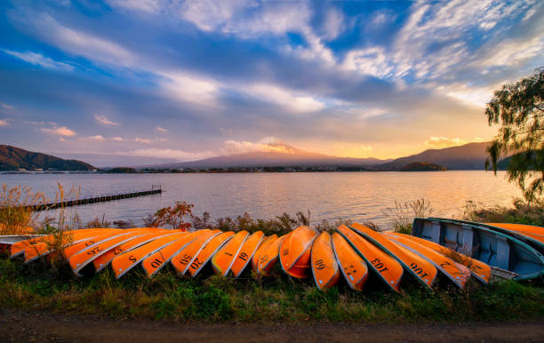 mt. fuji over lake kawaguchiko with boats at sunset in fujikawaguchiko, japan. - japan nautical vessel sakura tokyo prefecture stock-fotos und bilder