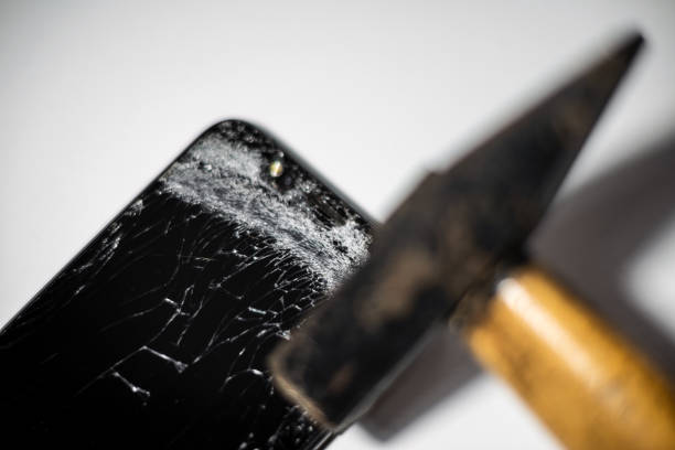 Hammer and smart phone with a broken screen.Electronics repair service. Crash smartphone.Indoors shot.