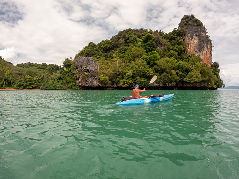 Man in his 60s canoeing in a bay in Southern Thailand enjoying winter in tropical climate.