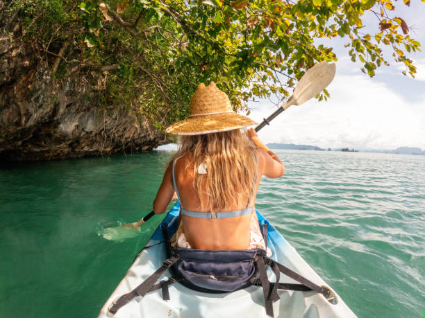 istock Young woman kayaking in tropical setting, rear view 1919810133