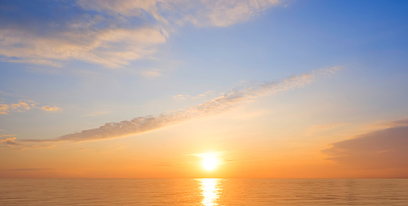 Majestic golden sunrise sky over sea with beautiful cloud and yellow sunlight reflection on water surface in the morning, Idyllic natural sunset seascape panoramic view background