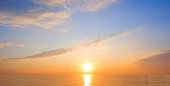 Majestic golden sunrise sky over sea with beautiful cloud and yellow sunlight reflection on water surface in the morning