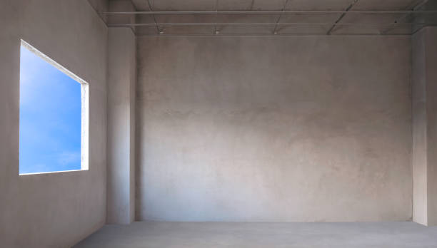 Perspective inside view of incomplete concrete interior wall room structure with blue sky view inside of panoramic window frame in house construction site
