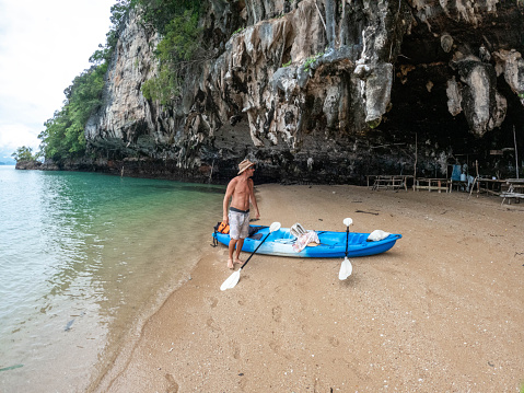 Male canoeing in a bay in Southern Thailand enjoying winter in tropical climate.