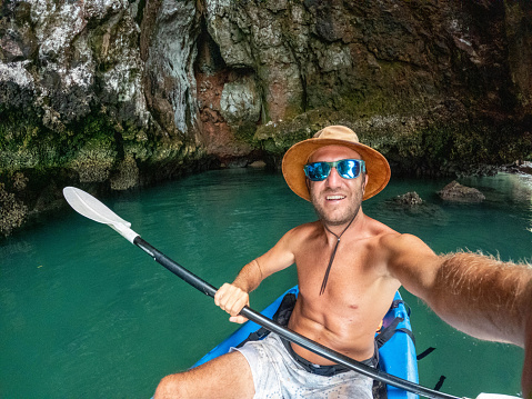 Man canoeing in a bay in Southern Thailand enjoying winter in tropical climate.