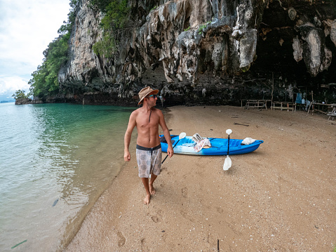 Male canoeing in a bay in Southern Thailand enjoying winter in tropical climate.