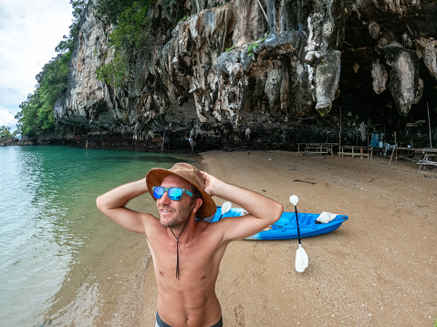 Male canoeing in a bay in Southern Thailand enjoying winter in tropical climate.