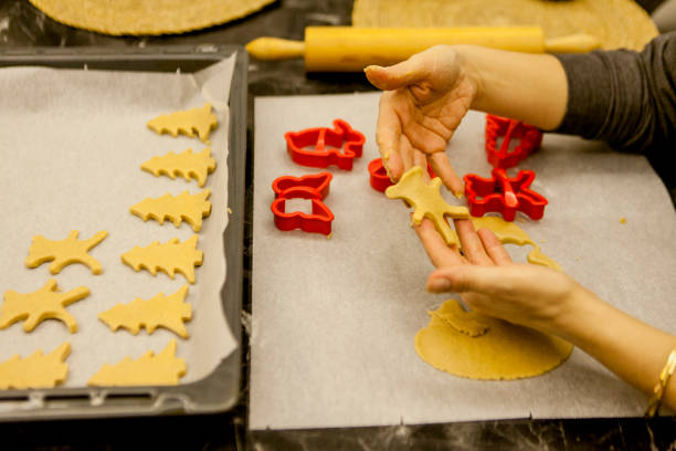 Various shapes made of raw pastry dough on a sheet of baking paper - preparation of homemade Linzer Christmas cookies