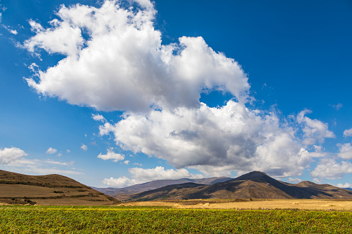 Landscape of the Armenian Caucasus mountains. Yellow-gold grass, wilde land and blue sky. Endless fields. Armenia.