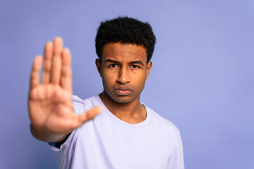 Young man showing a stop sign with his hand, serious expression.