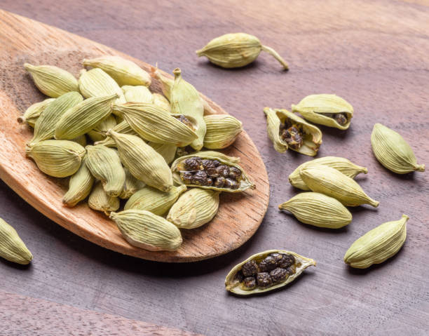 Cтоковое фото Seeds of cardamom spices in wooden spoon on a wooden table, mulled wine ingredient, macro image. Great spices background for your projects.