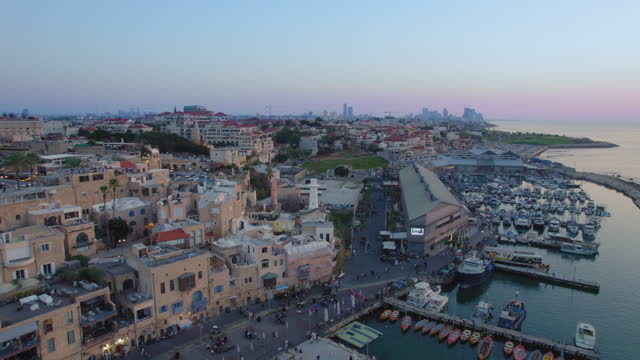 Old city of Jaffa and Jaffa port at sunset with lots of families visiting restaurants, shops and bars in the port - parallax drone shot