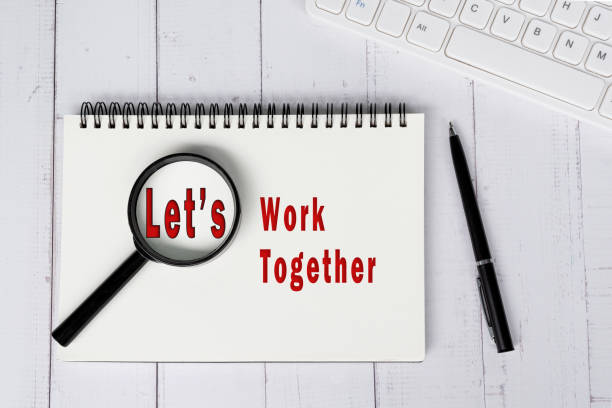 istock LET'S WORK TOGETHER text with magnify glass on note book on white w 1919948711