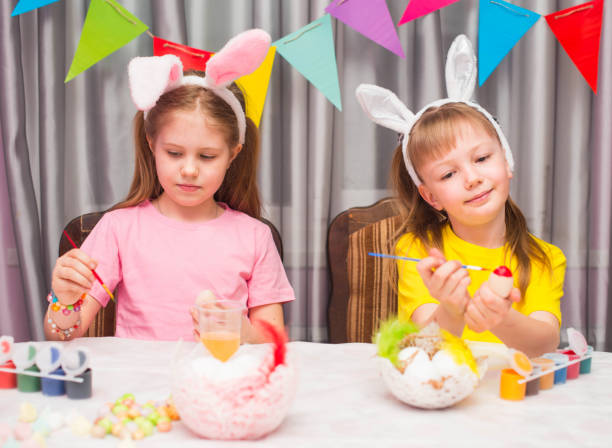 istock Children in bunny ears having fun painting eggs preparing for Easter. Happy easter! 1919961021