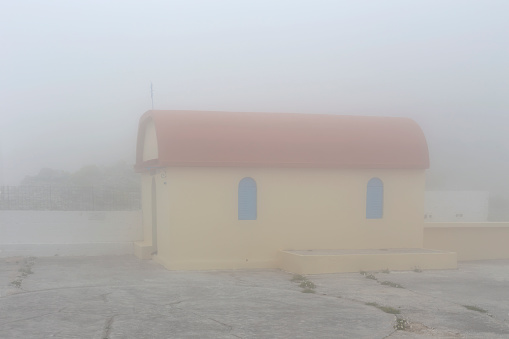 Small, Orthodox, Christian church in the mountains on a cloudy, foggy winter day