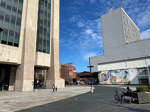 New York, NY USA - September 27, 2023 : People walking and sitting in the open plaza also known as African Square with colorful murals in front of the Adam Clayton Powell Jr. State Office Building on 125th Street in Harlem, New York City
