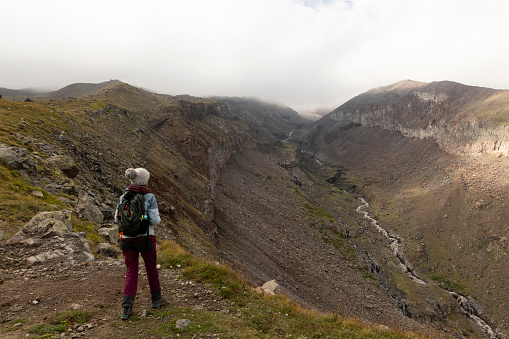 Woman trekking on mountain path in Georgia Caucasus mountains towards Kazbegi peak during summer