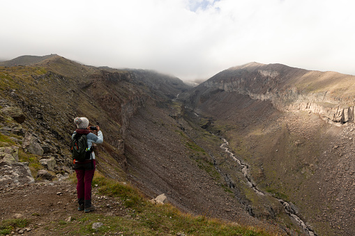 Woman trekking on mountain path in Georgia Caucasus mountains towards Kazbegi peak during summer